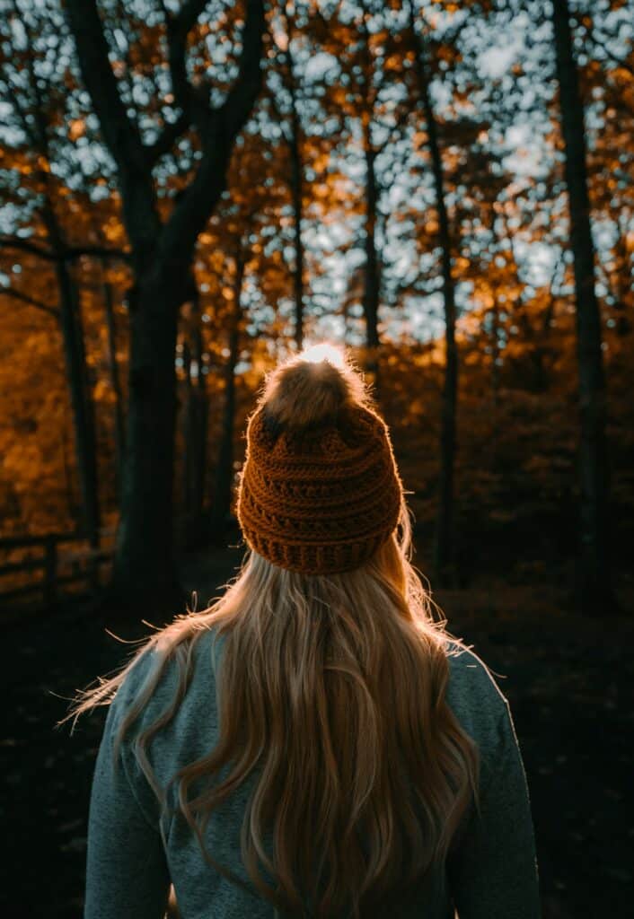 a woman wearing a knit hat and looking at trees