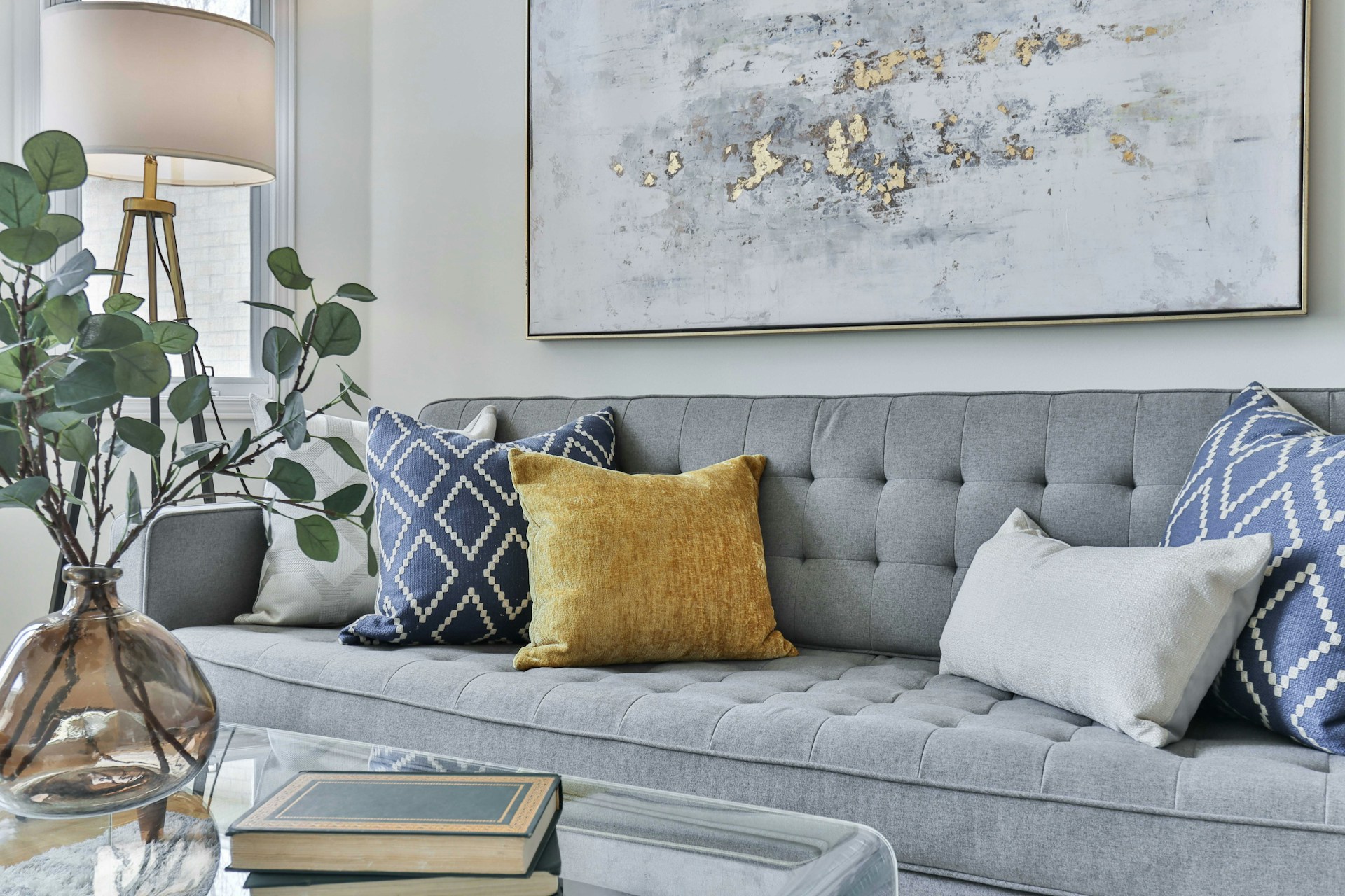 a couch with pillows and a lamp in front of a painting