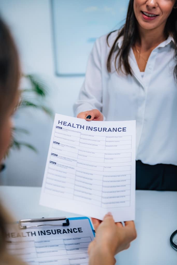 Woman examining her health insurance form to determine coverage for substance use treatment.